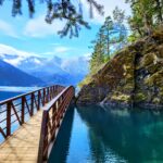 Crystal-clear waters of Lake Crescent under a wooden bridge at Olympic National Park, surrounded by rugged terrain and evergreen trees, inviting a peaceful moment during a one-day trip."