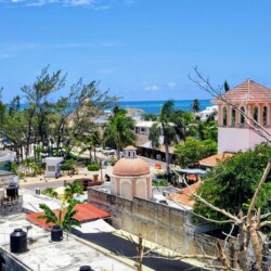 Elevated view of Puerto Morelos town with traditional buildings and a glimpse of the sea, capturing the essence of the destination near Cancun.
