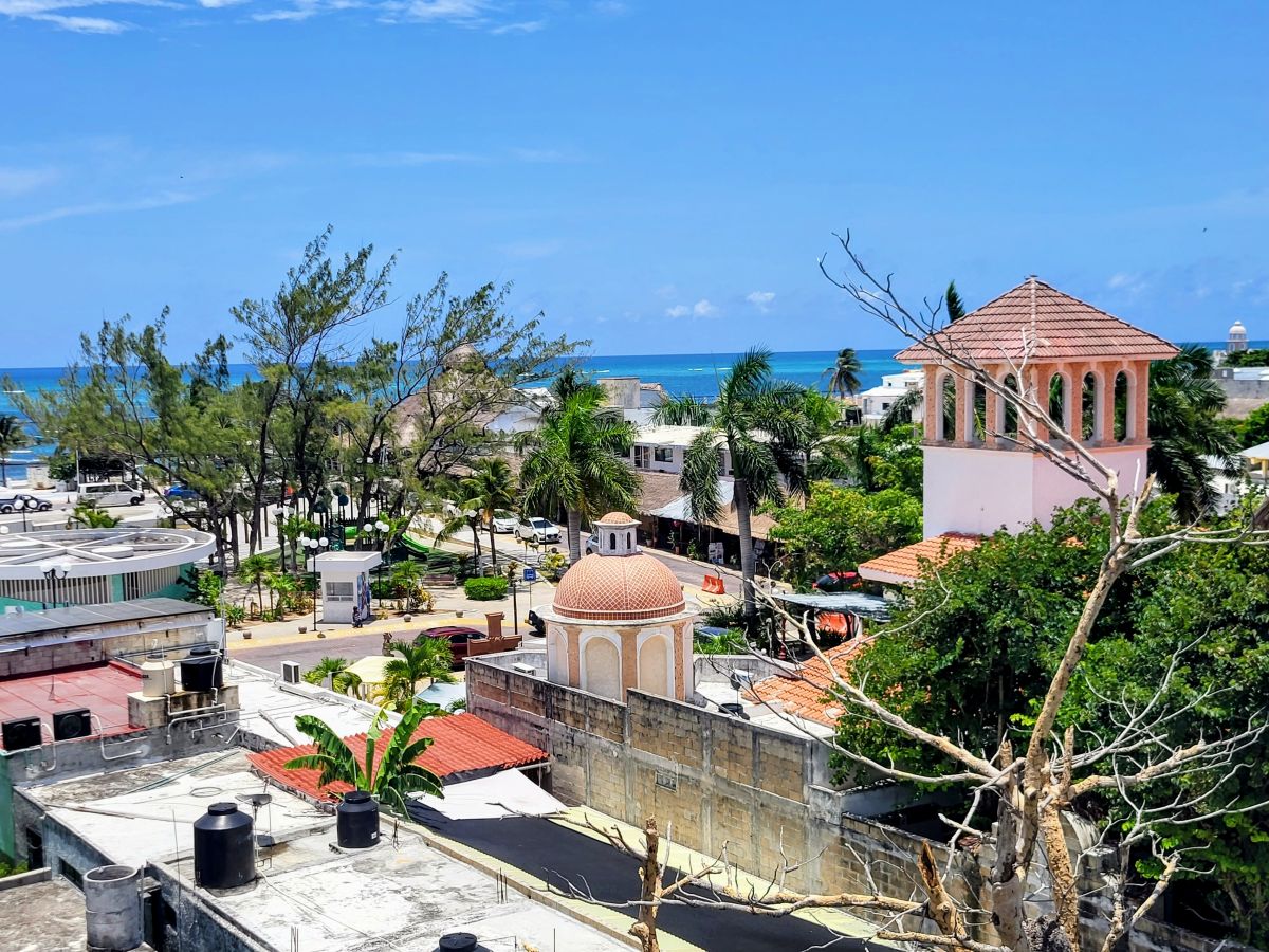 Elevated view of Puerto Morelos town with traditional buildings and a glimpse of the sea, capturing the essence of the destination near Cancun.