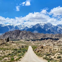 A long dirt road stretches towards the imposing Sierra Nevada mountains, offering a striking view during an Alabama Hills hike.
