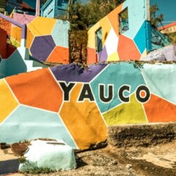 Colorful mural spelling out 'Yauco' on a staircase in Yauco, Puerto Rico, showcasing a vibrant pattern of geometric shapes in a kaleidoscope of colors. A sunny day enhances the vividness of the mural, inviting visitors to explore the best things to do in Yauco.