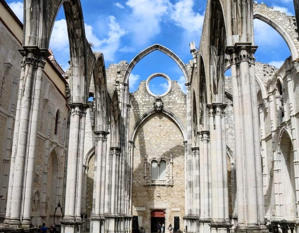 The sky peeks through the roofless arches of the Carmo Convent ruins in Lisbon, a historical site that offers a glimpse into the past, ideal for inclusion in a culturally rich Lisbon itinerary.