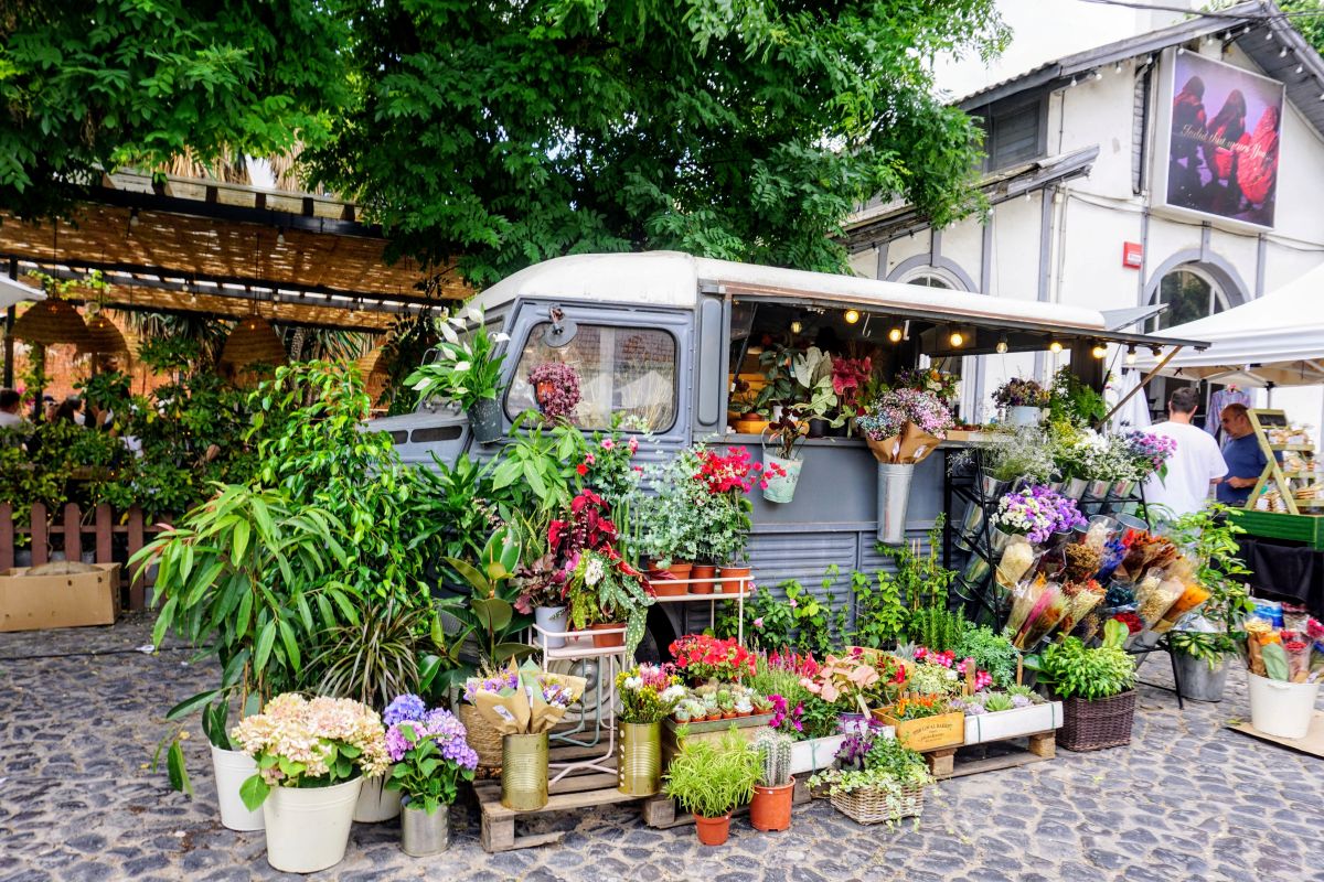 Vibrant flower market set up in a vintage van, with an array of colorful plants and bouquets, at the LX Factory in Lisbon, offering a unique shopping experience for a Lisbon itinerary.