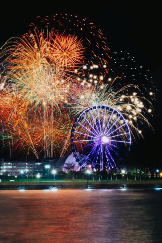 Colorful fireworks light up the sky over Chicago's Navy Pier Ferris Wheel and Lake Michigan's waterfront.