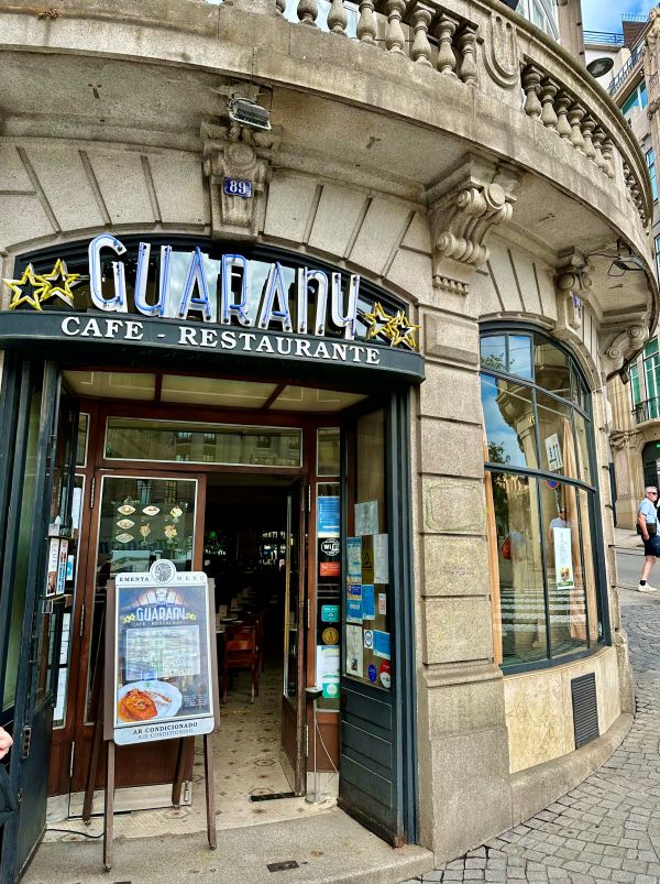 Entrance of Café Guarany in Porto with its iconic neon sign, welcoming visitors and locals alike, a must-visit cafe for coffee enthusiasts.