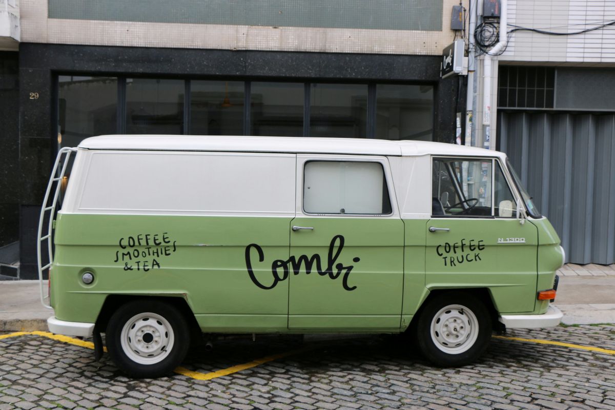 Vintage green and white Combi coffee truck parked on a cobblestone street in Porto, offering a unique cafe experience with coffee, smoothies, and tea.