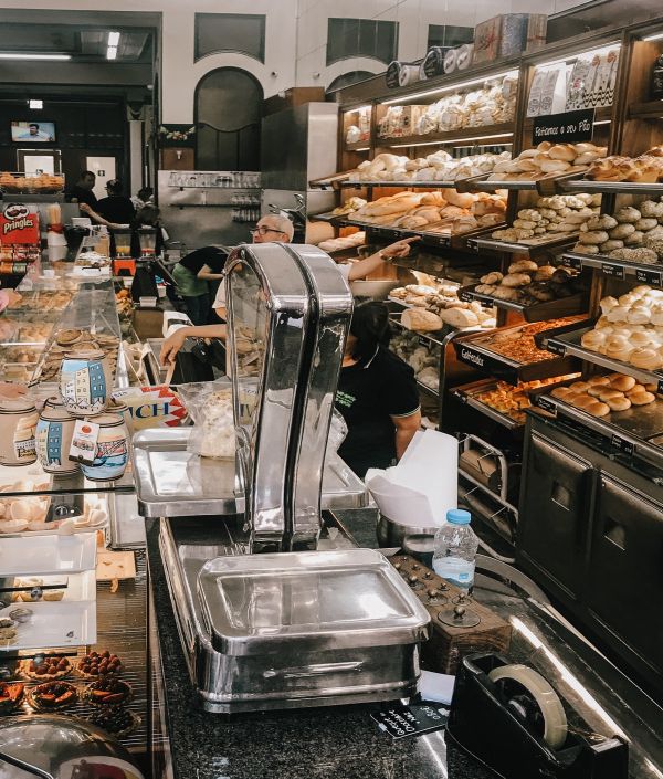 Busy interior of Confeitaria de Bolhão, a traditional Porto cafe and bakery, showcasing a variety of Portuguese pastries and bread, perfect for a coffee break.