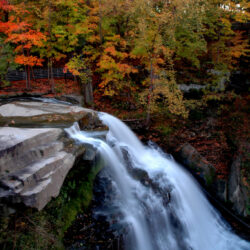 Cascading waters of Brandywine Falls surrounded by a vibrant display of fall foliage in the Midwest at Cuyahoga National Park.