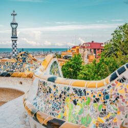 Mosaic serpentine bench curving along the terrace of Park Güell, offering panoramic views of Barcelona, a picturesque inclusion in a Barcelona travel itinerary.