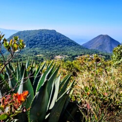 A landscape view from El Salvador's Santa Ana Volcano trail. Clear skies above volcanic and mountainous views.